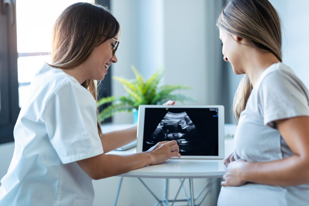 Médico ginecólogo mostrando ingenio de bebé de ecografía embarazada