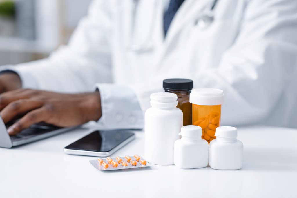 Primer plano de diversos tipos de medicamentos en la mesa del médico africano, pastillas para coronavirus